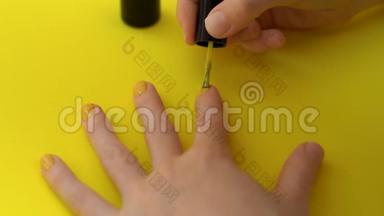 一个女孩在<strong>黄色</strong>背景下把指甲涂成<strong>黄色</strong>的特写镜头。 <strong>黄色</strong>概念。